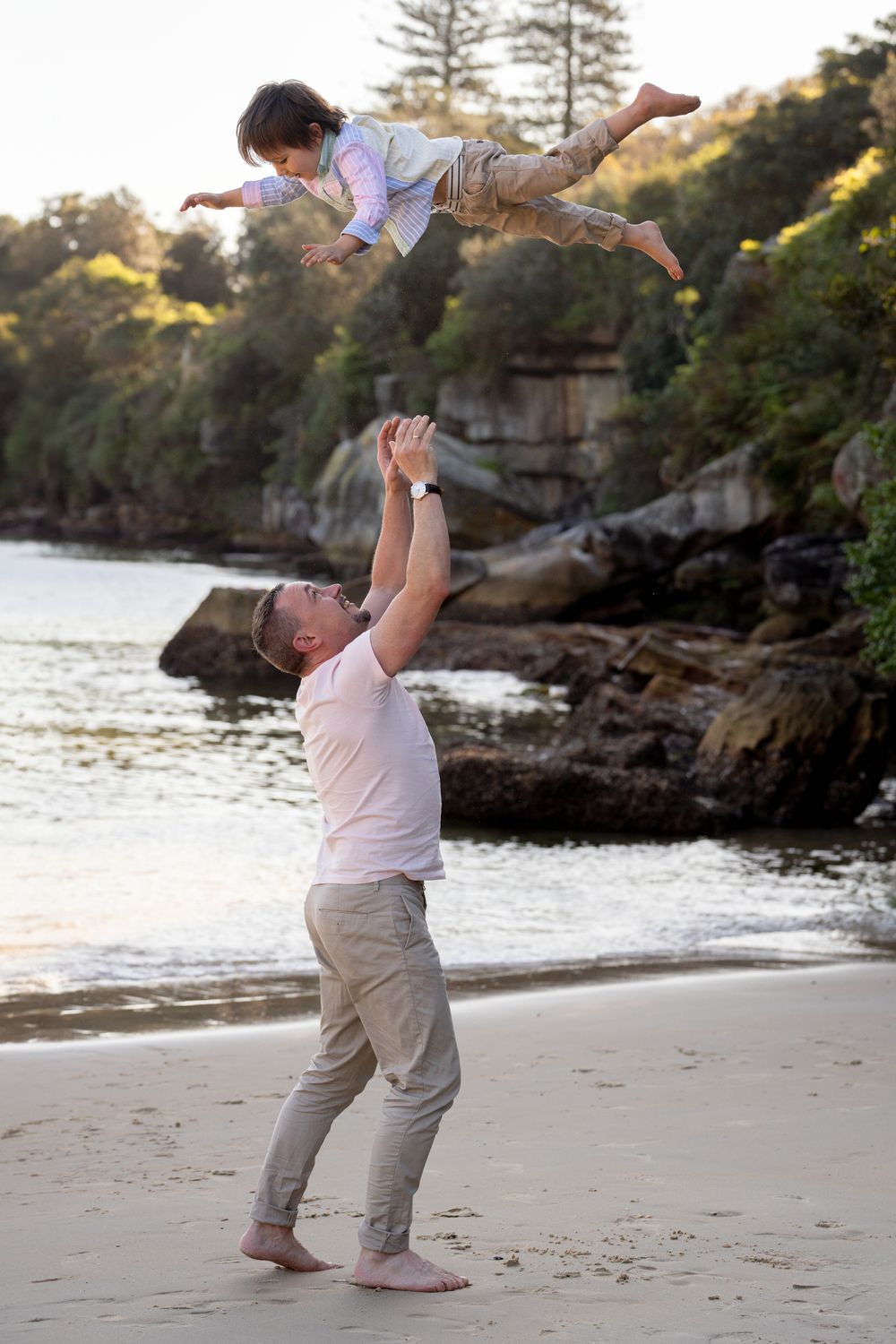 Dad playfully throwing his son into the air during a family photoshoot in Sydney, capturing a joyful and moment