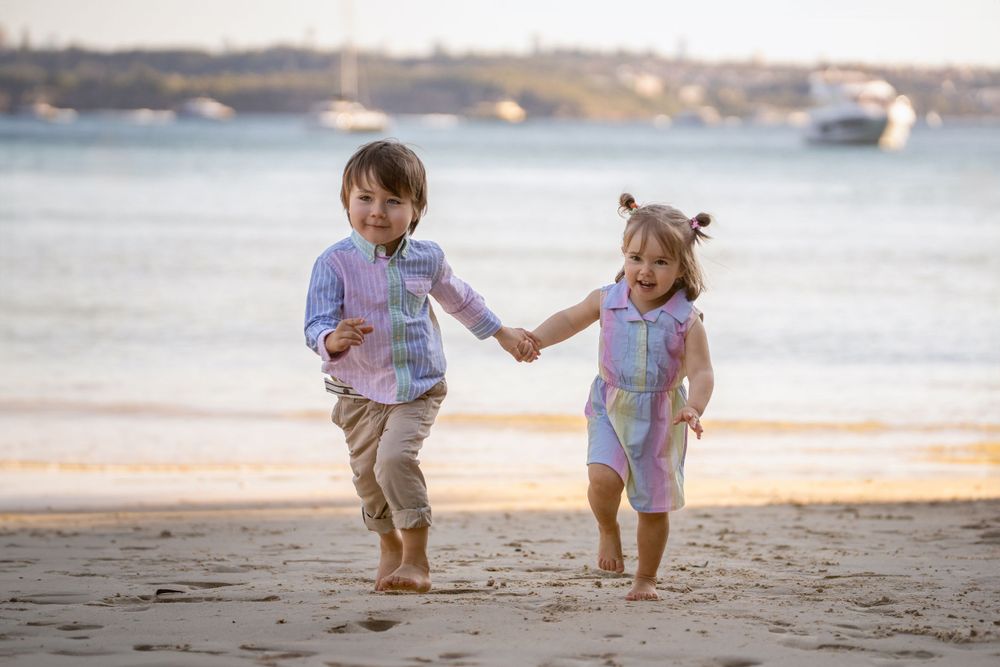 Siblings running towards the camera at Northern Beaches during a family photoshoot, showcasing their energy and bond