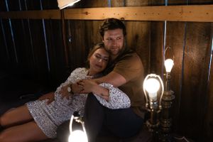 Intimate couple's portrait in dark wooden room with glowing vintage lights.