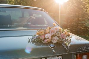 Vintage BMW decorated with romantic floral arrangements captured in warm evening light.