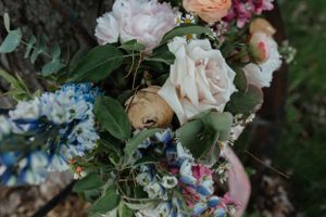 Close-up of a lush floral arrangement featuring roses, blue flowers, and greenery.