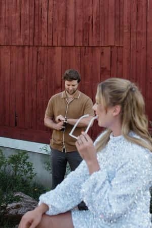 Casual outdoor scene by red barn with drinks and casual conversation.