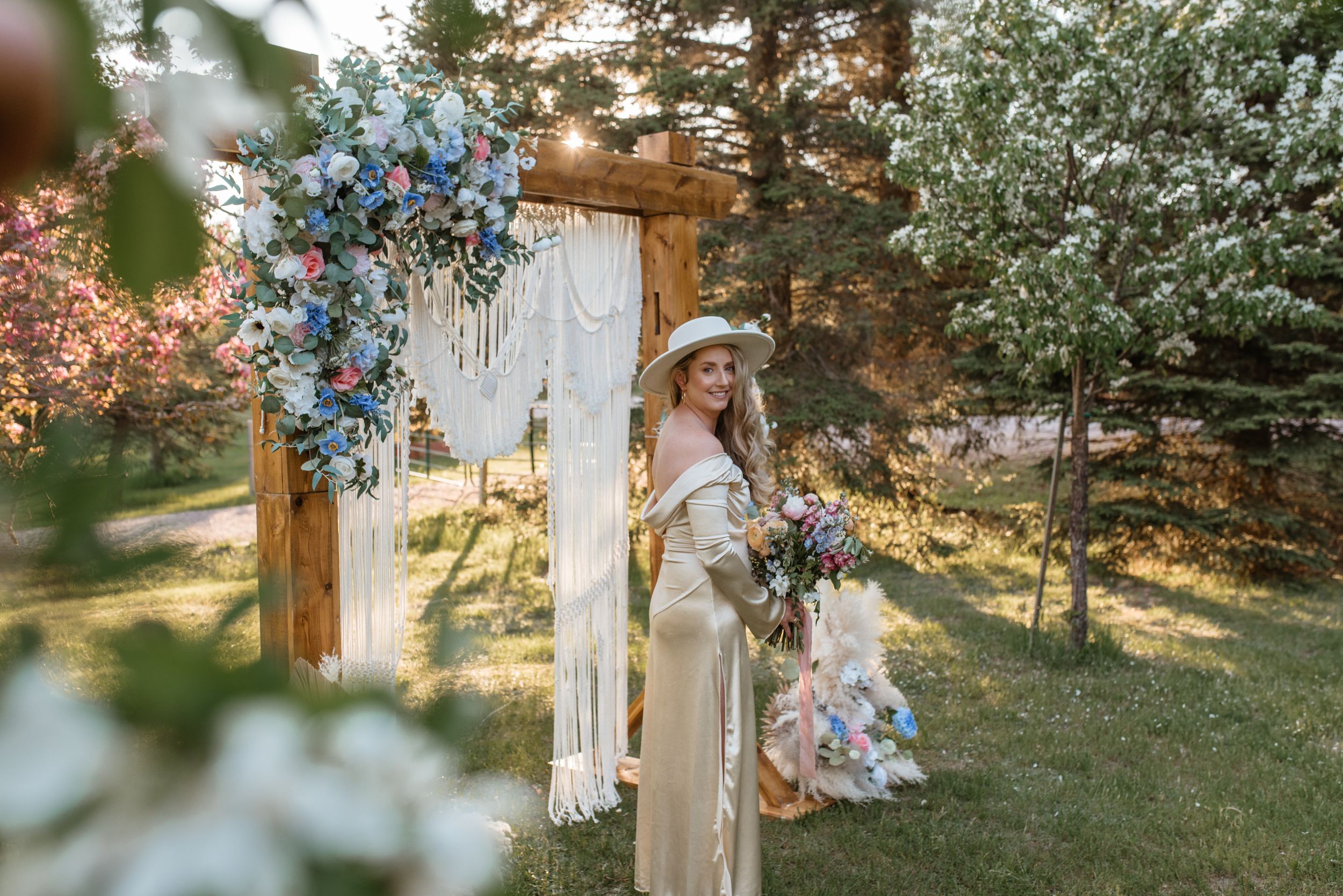 Dreamy boho wedding scene with floral arch and delicate details in garden setting.