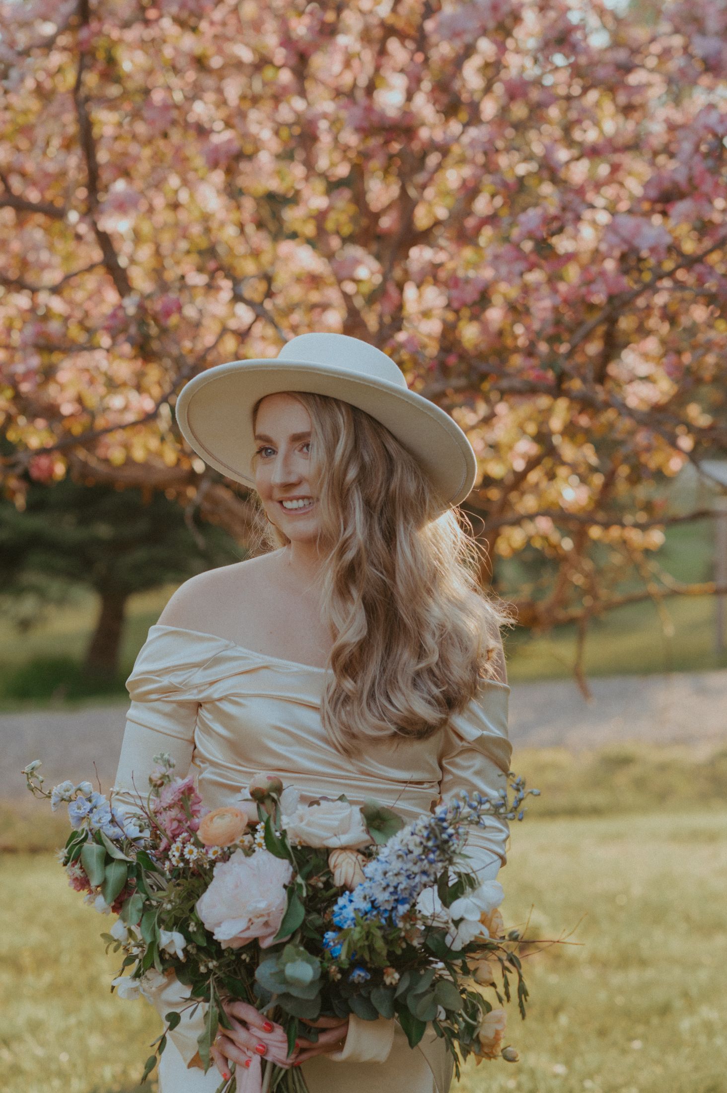 Elegant springtime portrait with cherry blossoms and a delicate bouquet of mixed flowers.