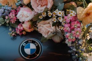 Elegant floral arrangement placed beside a BMW emblem on a car's hood.