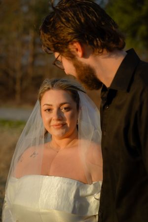 A tender moment between newlyweds during golden hour as they embrace outdoors in wedding attire.
