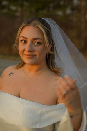 Close up portrait of a bride in a white off-shoulder wedding dress and veil during golden hour.