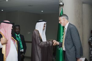 Government officials and diplomats meet in formal setting with Saudi Arabian flag visible during diplomatic engagement.