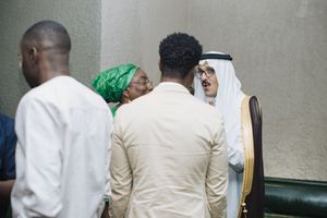 People in traditional Middle Eastern and African attire having a discussion in an indoor setting.