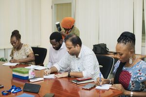A group of people sit at a conference table taking notes during a business meeting.