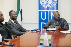Meeting participants seated at a conference table with UNDP logo visible in the background.