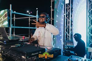 DJ performs behind turntables at night event wearing white jacket and headphones with blue stage lighting.