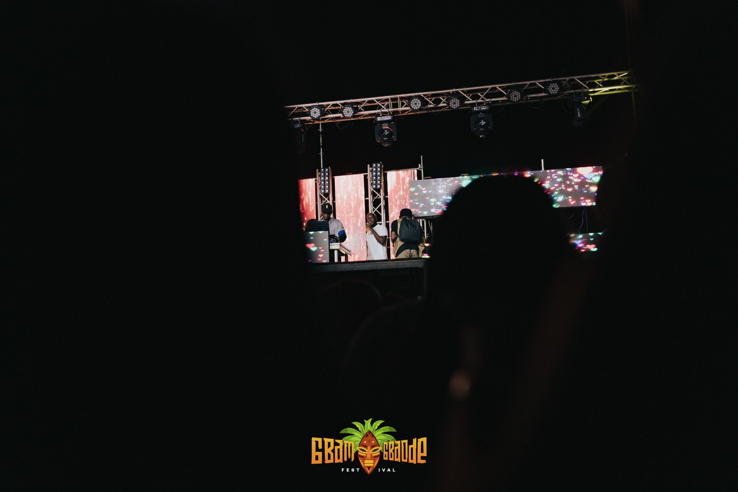 Dark silhouette of stage equipment and lighting rigs against a dimly lit concert or event setting.