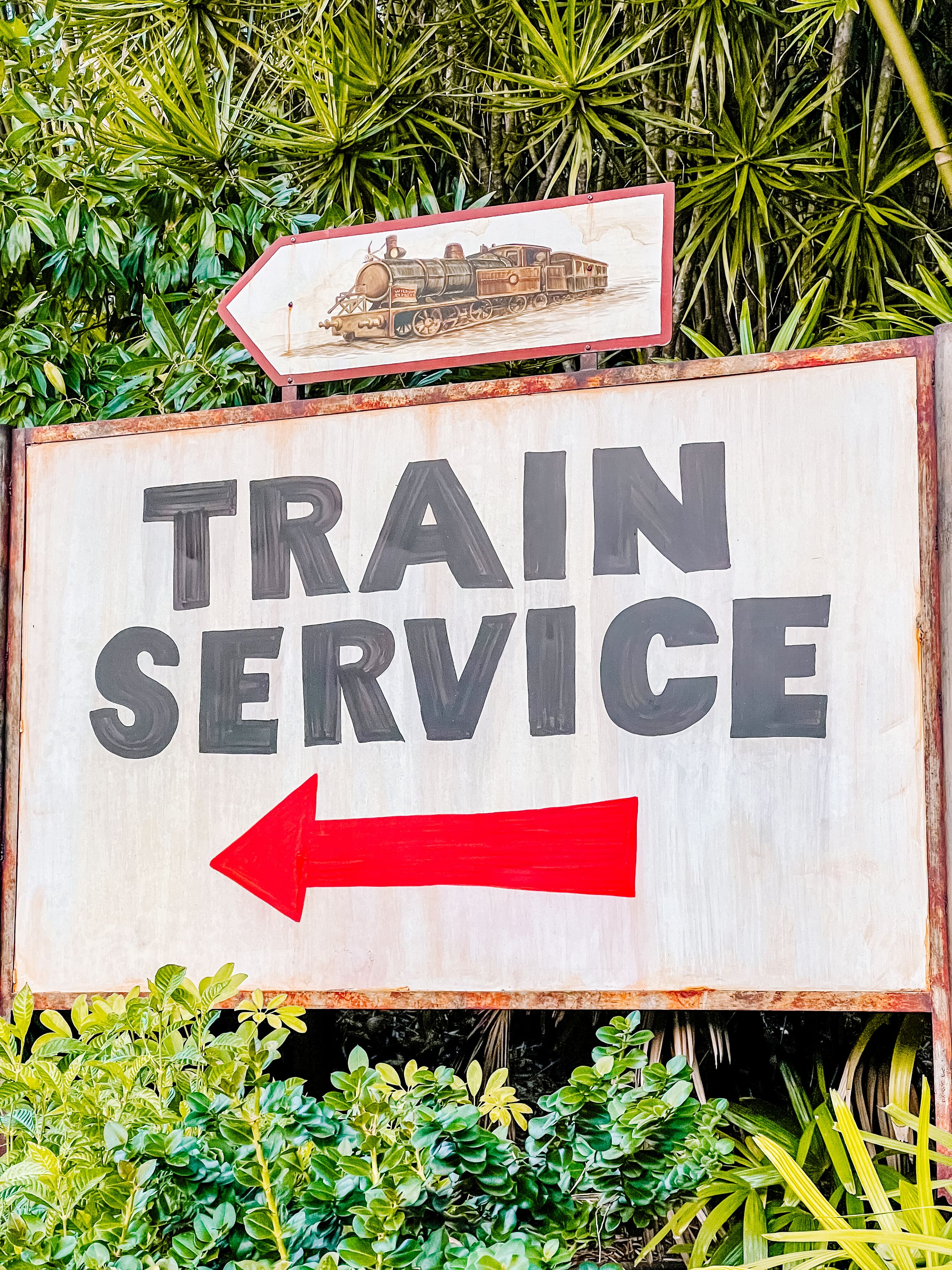 Vintage style train service directional sign with red arrow and locomotive illustration.