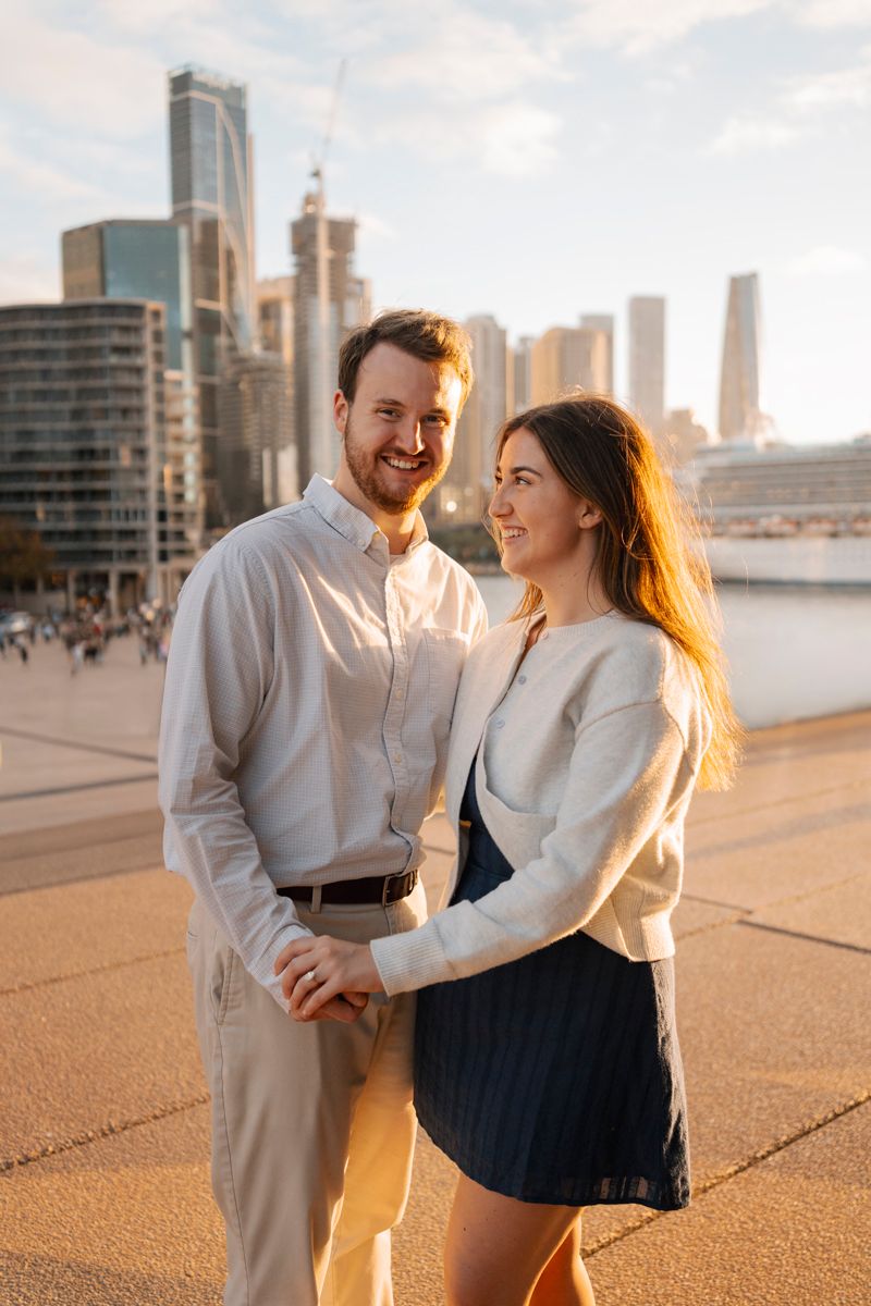 couple smiling and having fun during an engagement photoshoot in Sydney during a setting sun light with an orange glow.