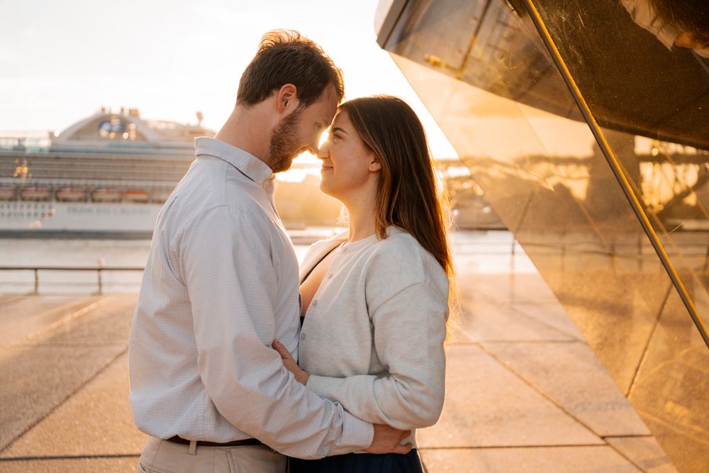 intimately hugging couple in the orange glowing sunset hugging during a proposal photoshoot near the Sydney Opera house