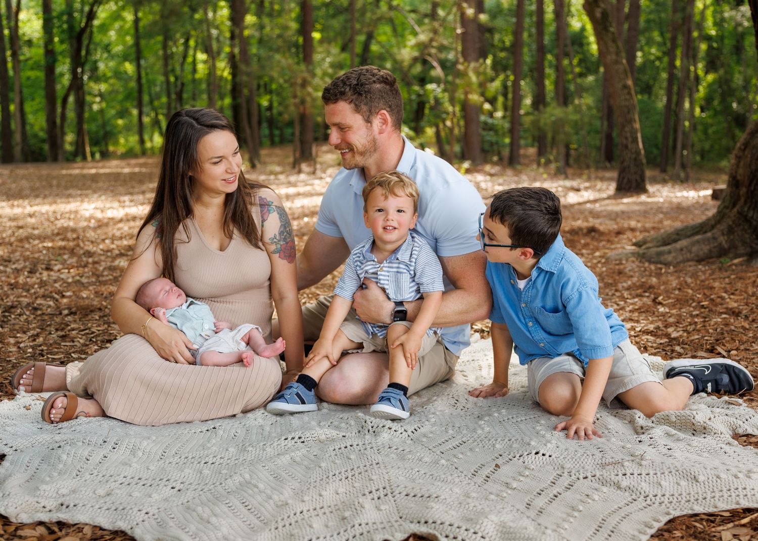 Parents walking through a field hand-in-hand with their daughter during a golden hour family session by Raley & Roots.