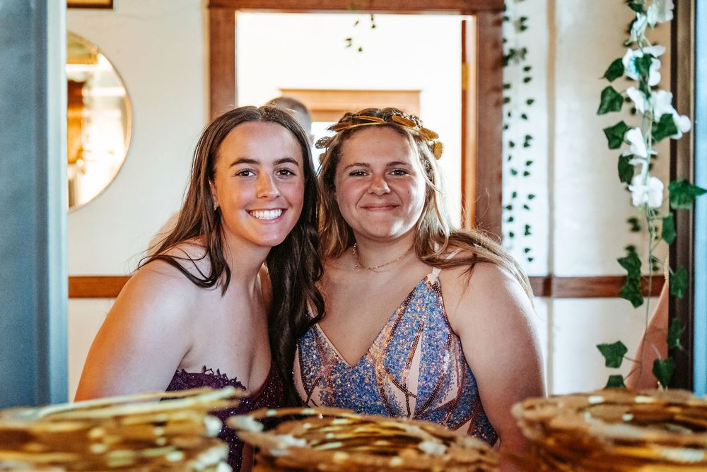 Two friends share a joyful moment at a restaurant table filled with food.