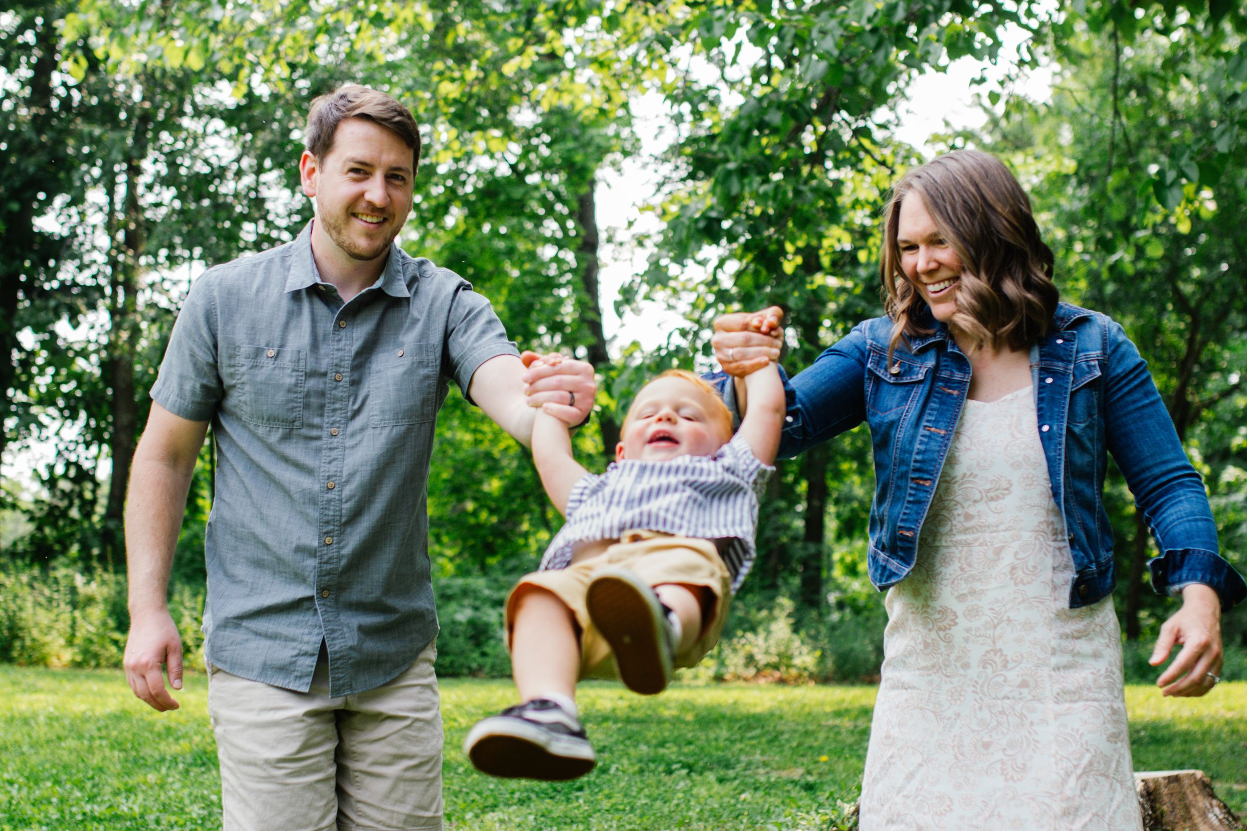 A family shares playful moments together in a lush green park setting.