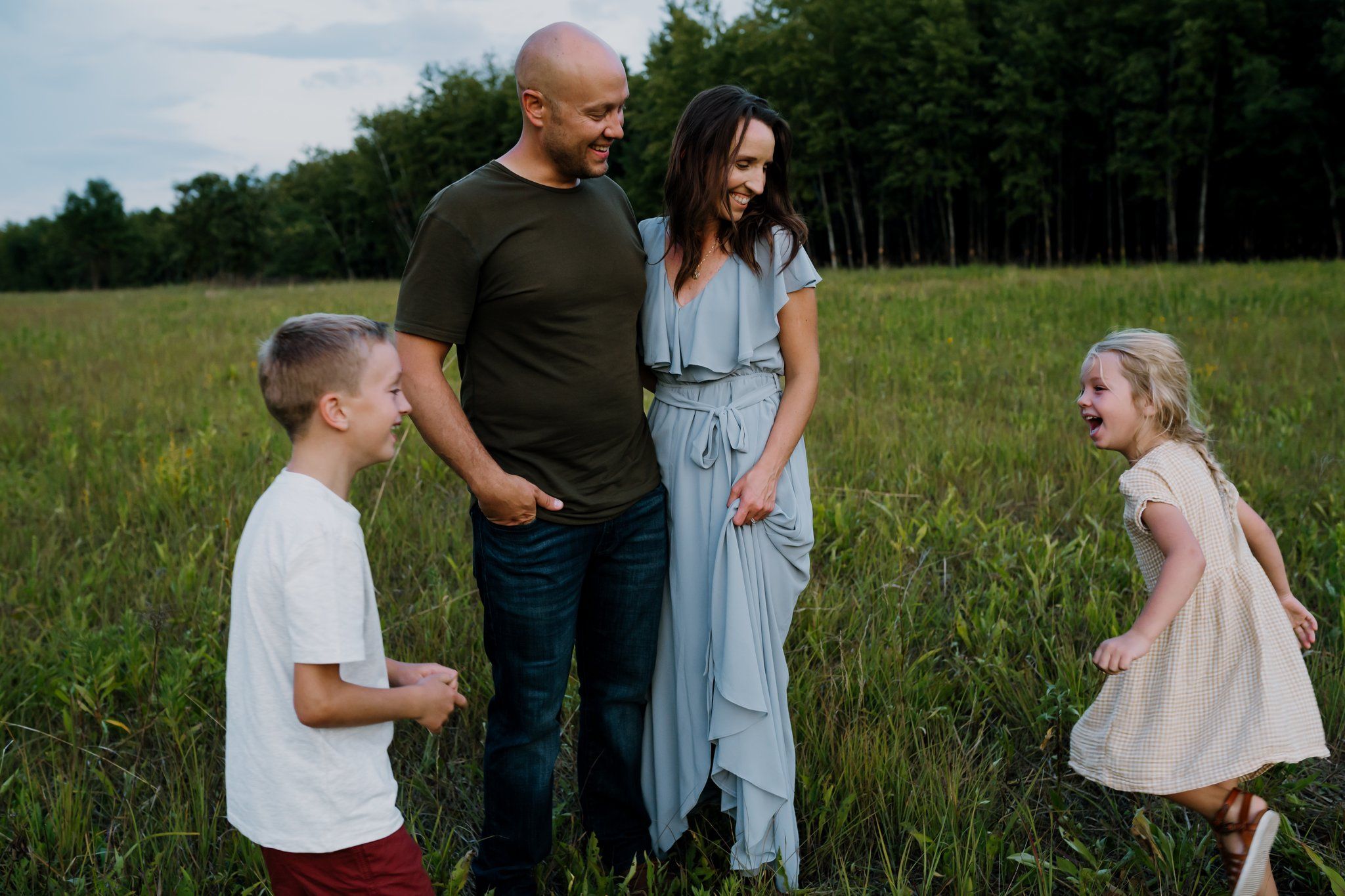 Parents smile as kids run around them laughing during family pictures in knoxville tn