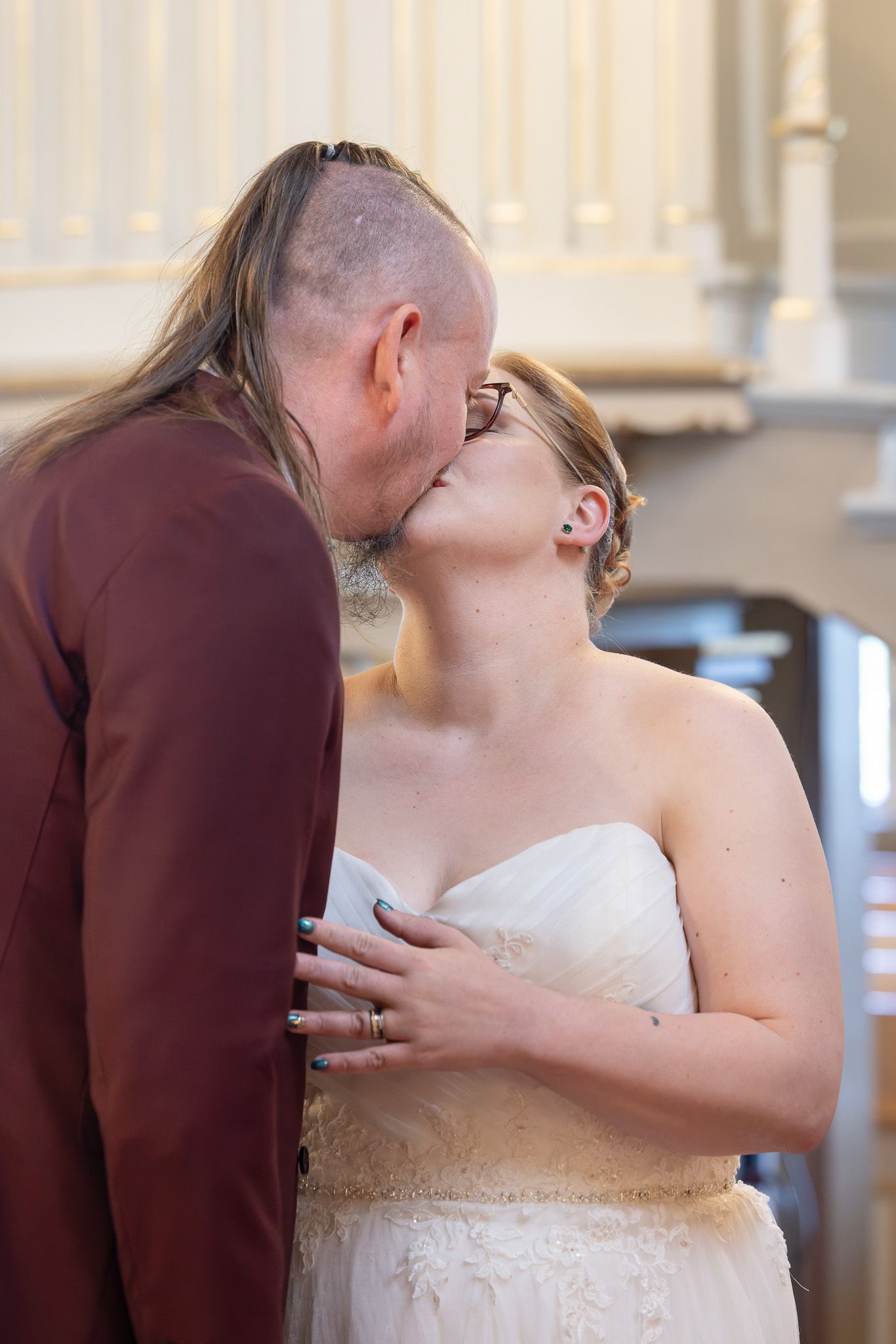 A couple shares a romantic kiss during their wedding ceremony, with the bride wearing a white strapless gown.