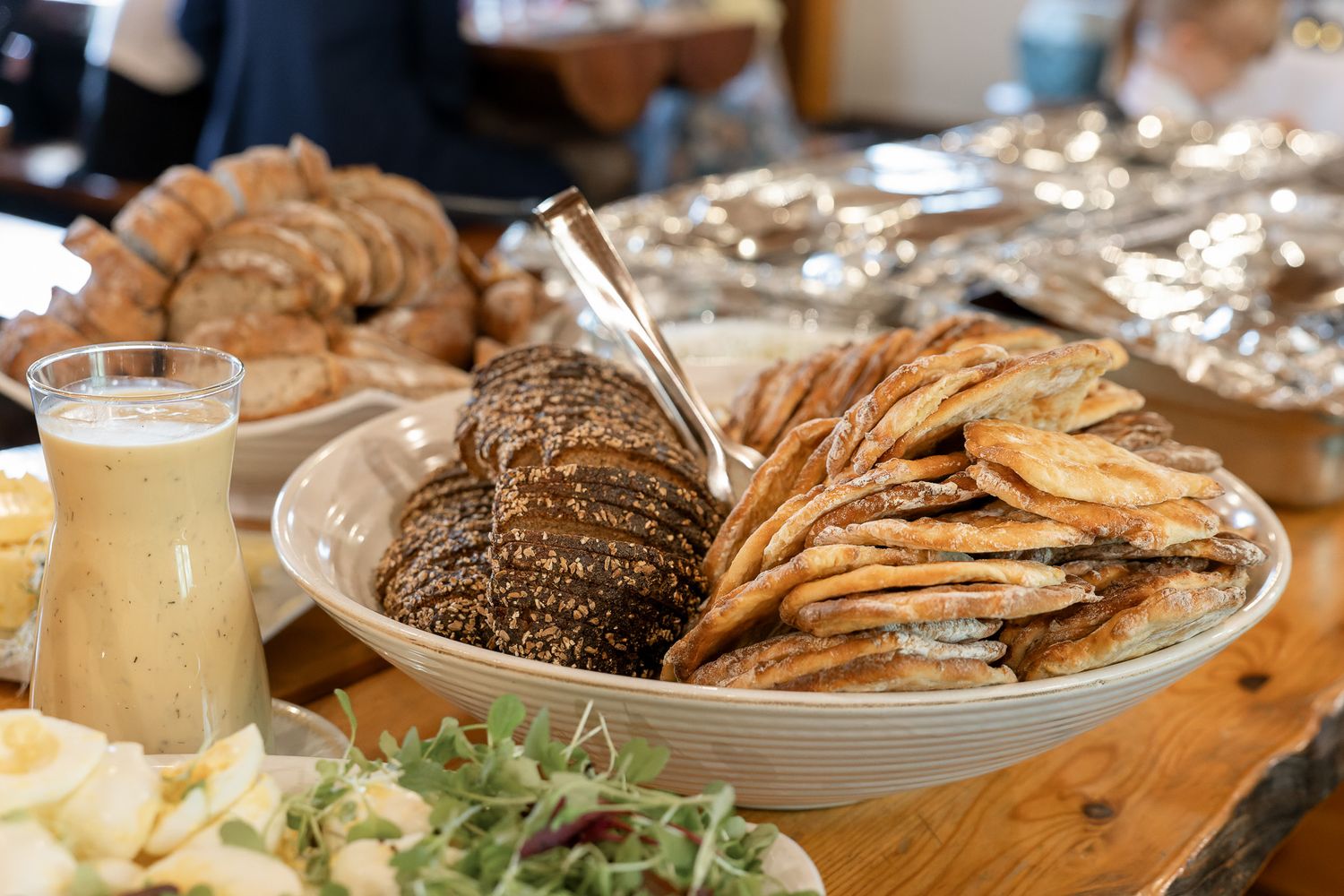 Assorted seafood dishes and appetizers served on wooden table with drinks and garnishes.