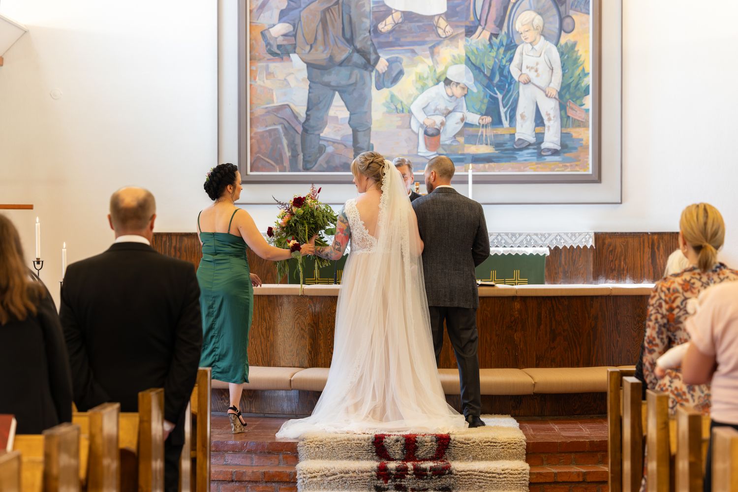 Bride and groom stand at the altar during a church wedding ceremony, with guests seated in wooden pews.