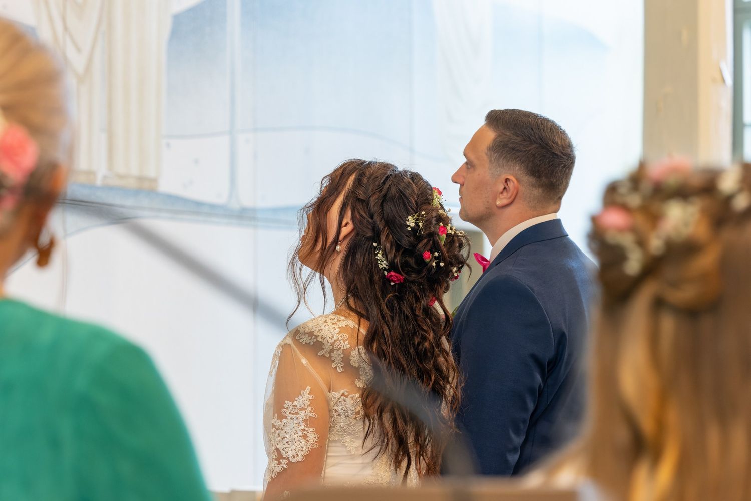 A couple shares a tender moment during their wedding ceremony in an elegant venue with soft lighting.