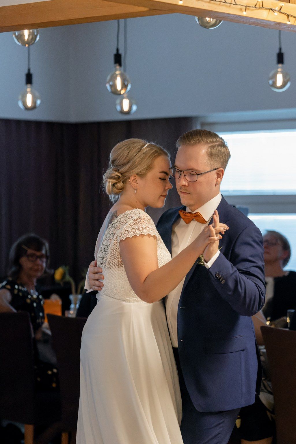 Hääpari tanssiin valssia. Yläpuolella koristevalaisimia.