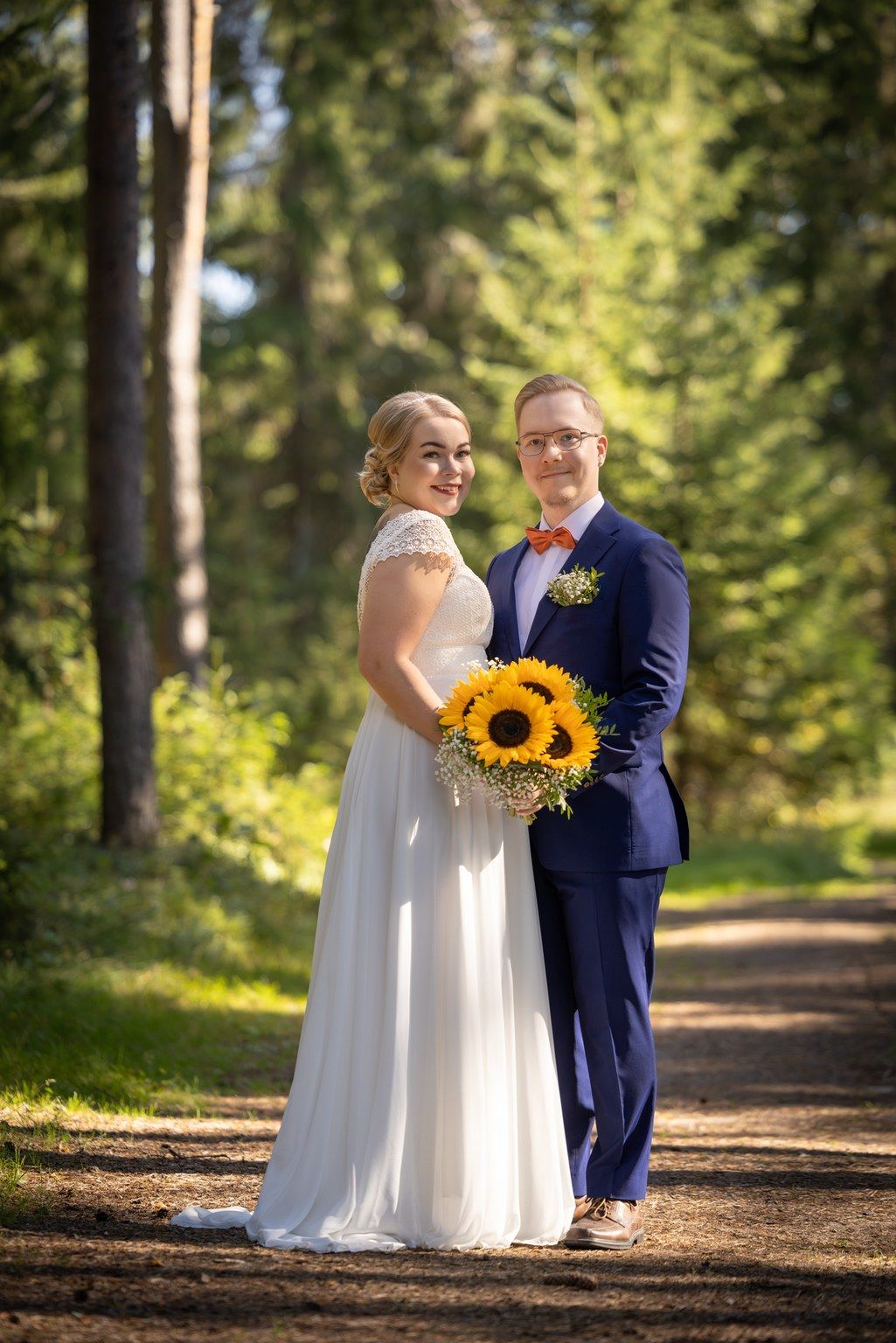 Hääpari metsäisessä maisemassa metsäpolulla.
