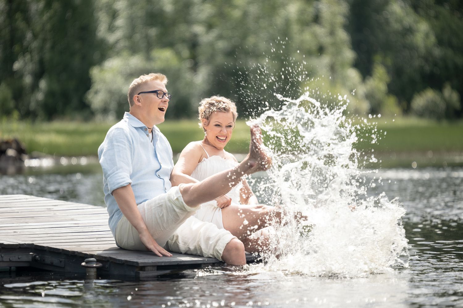 Hääpari porskuttaa jaloillaa vettä laiturilla.