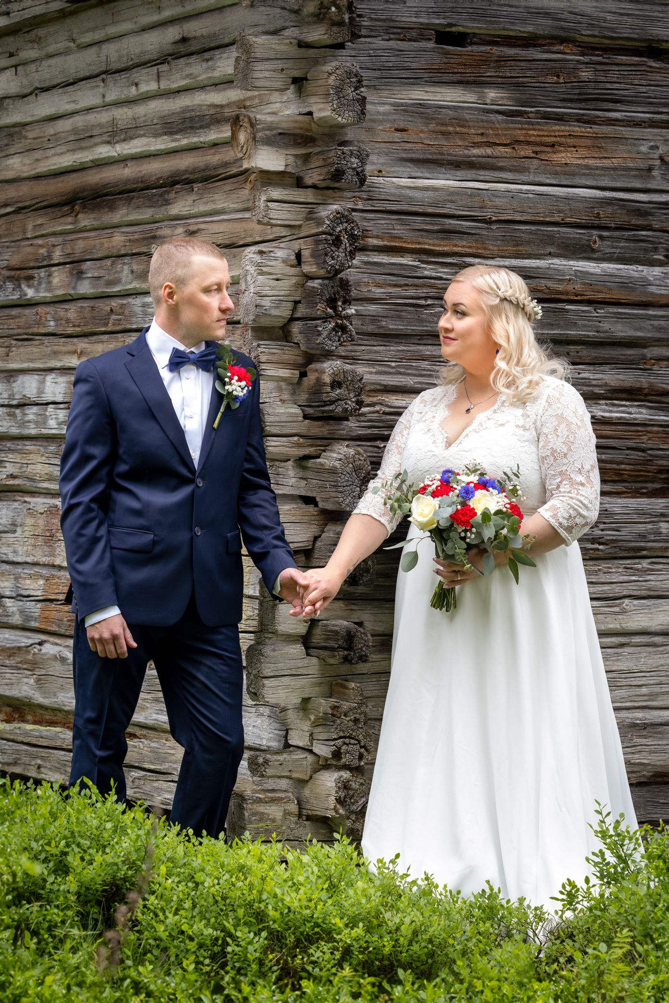 Hääpari seisoo toisiinsa katsoen vanhan rakennuksen kulmalla.