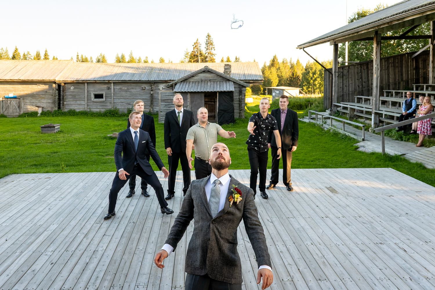 Sulhanen heittää sukkanauhan takanaan seisoville miehille.
