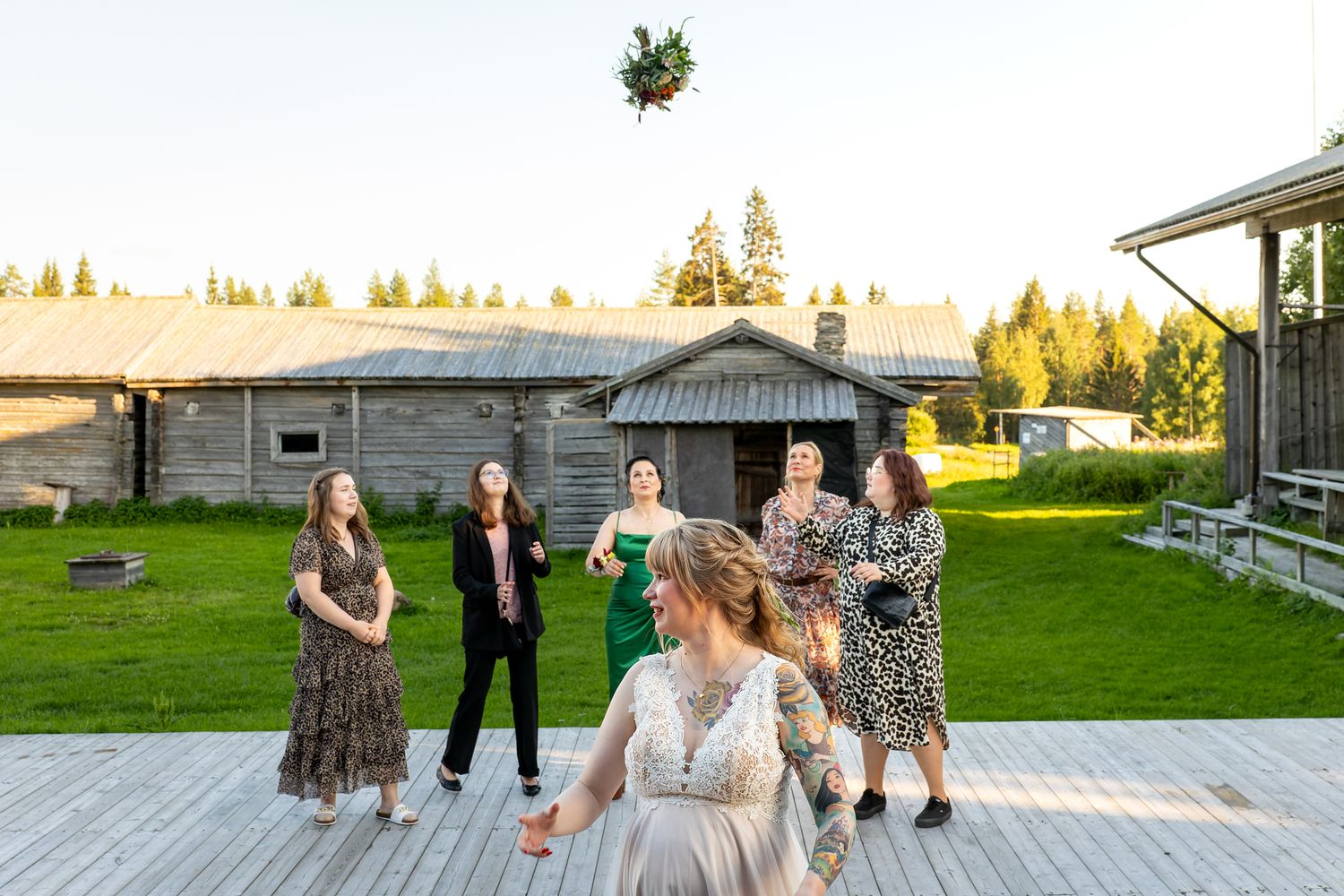 Morsian heittää hääkimpun takanaan seisoville naisille.