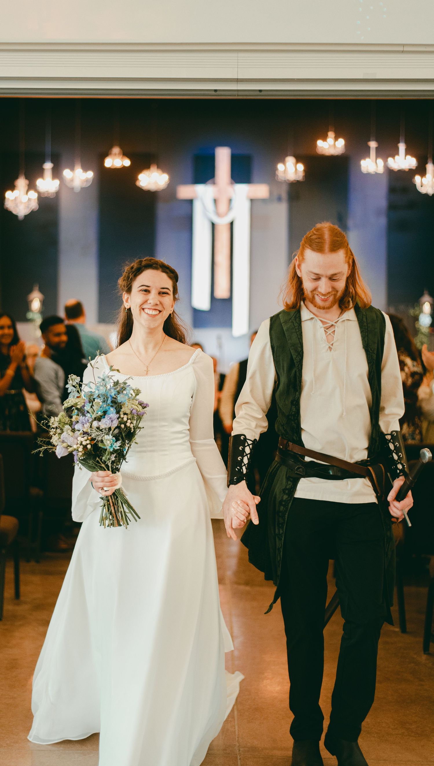Bride and groom walking down aisle together happily holding hands, now married