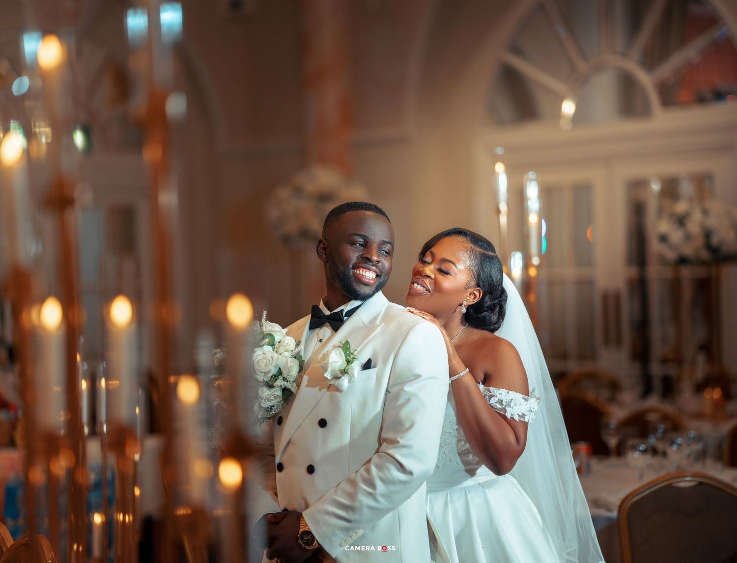Joyful couple shares a romantic moment during their wedding reception surrounded by candlelight.