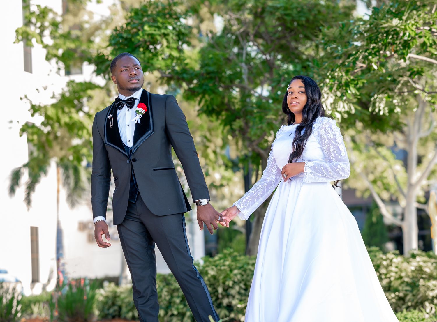 Bride and groom holding hands, captured by Palm Beach wedding photographers near a coastal garden venue.