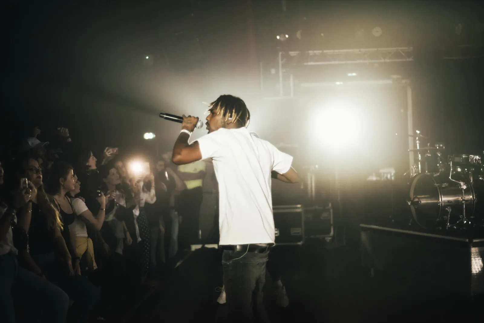 Performeur en pleine interaction avec la foule, dos au projecteur, capté dans une ambiance lumineuse et immersive.