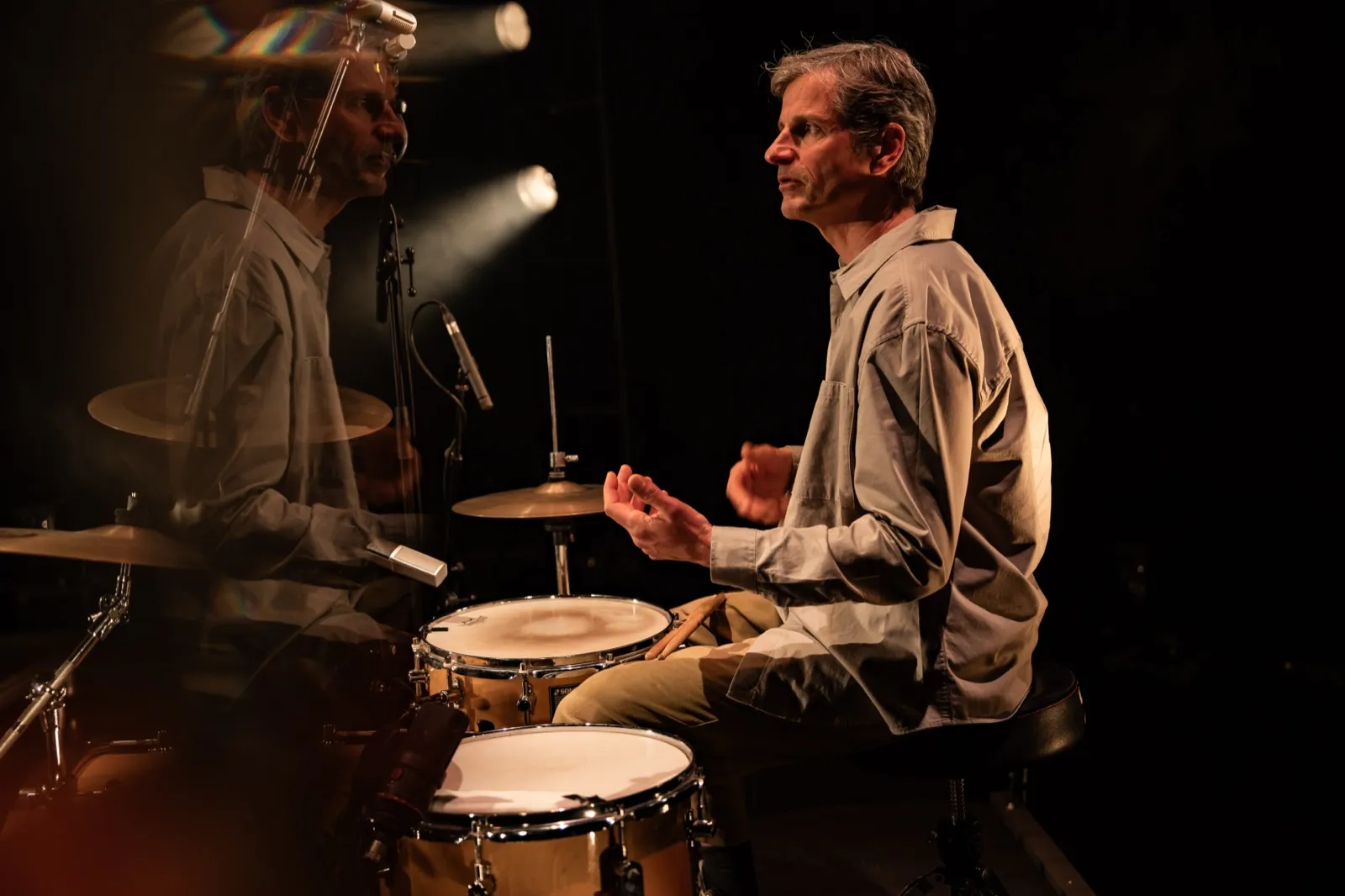 Percussionnistes jouant, éclairé par des projecteurs chauds dans une ambiance intimiste.