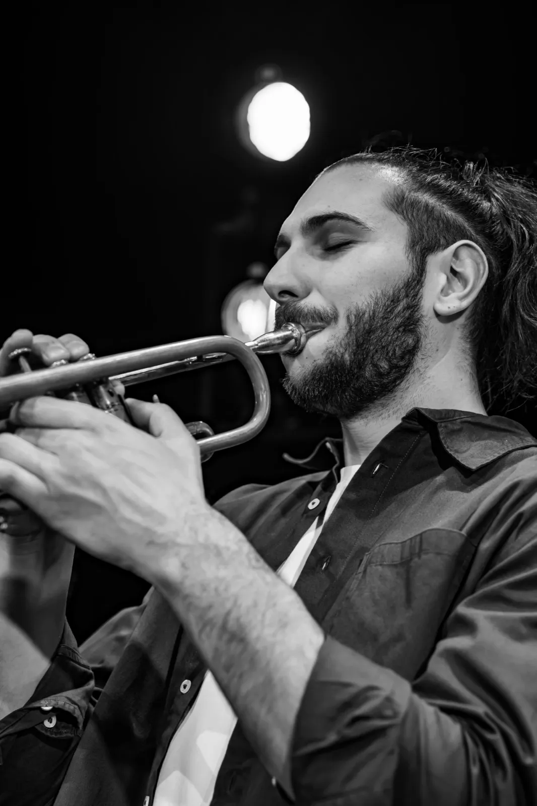 Portrait en noir et blanc d’un chanteur concentré, tenant un micro en chantant, éclairé par une lumière douce.