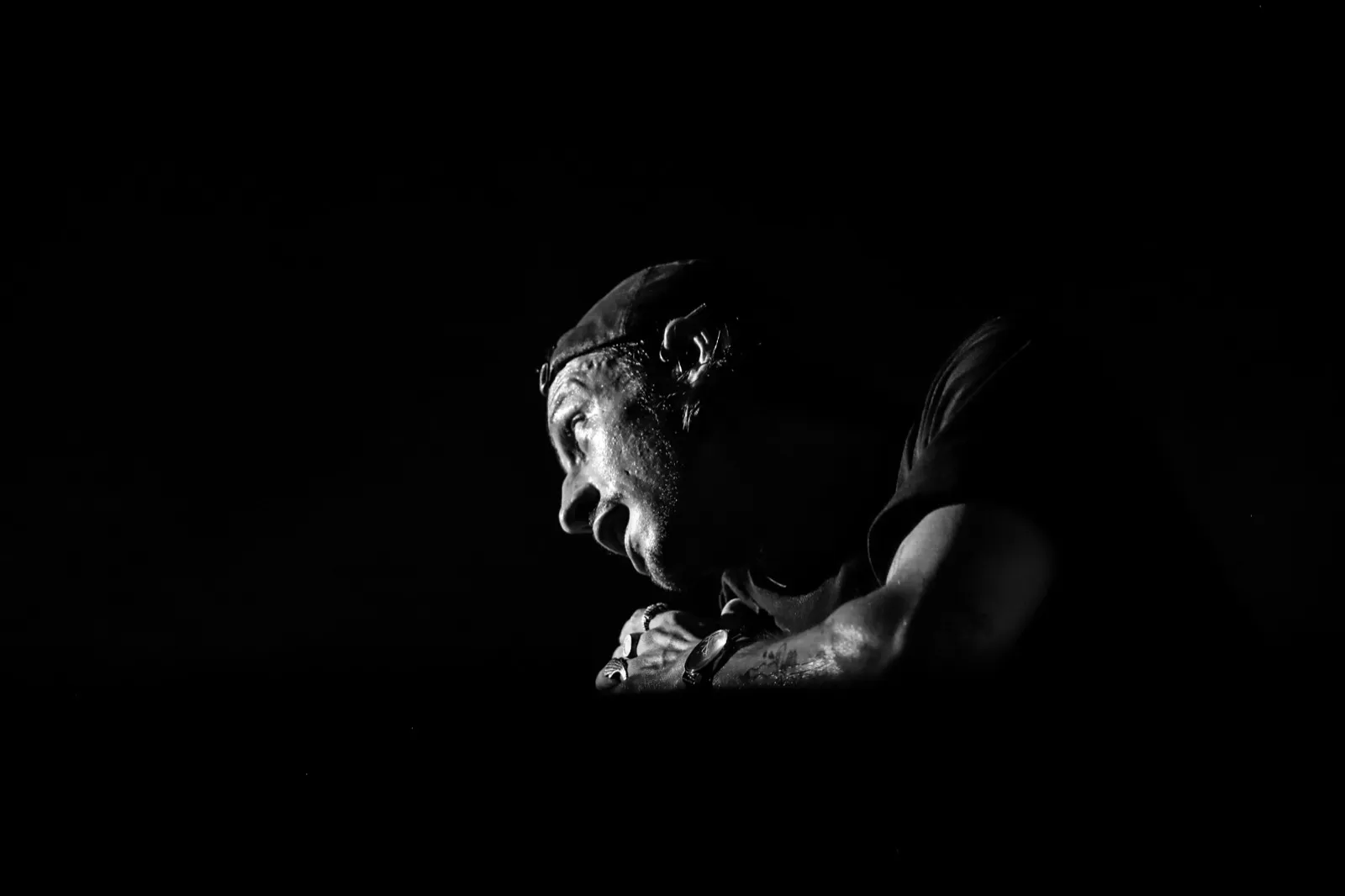 Silhouette pensive de l’artiste en noir et blanc, mains croisées devant le visage dans un moment suspendu.