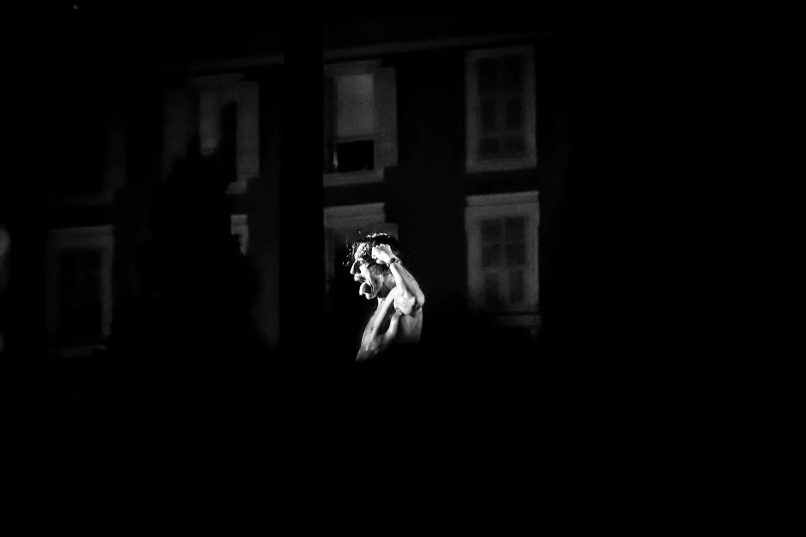 Un artiste en train de marcher ou danser, éclairé depuis le haut, créant une silhouette expressive dans l’obscurité.