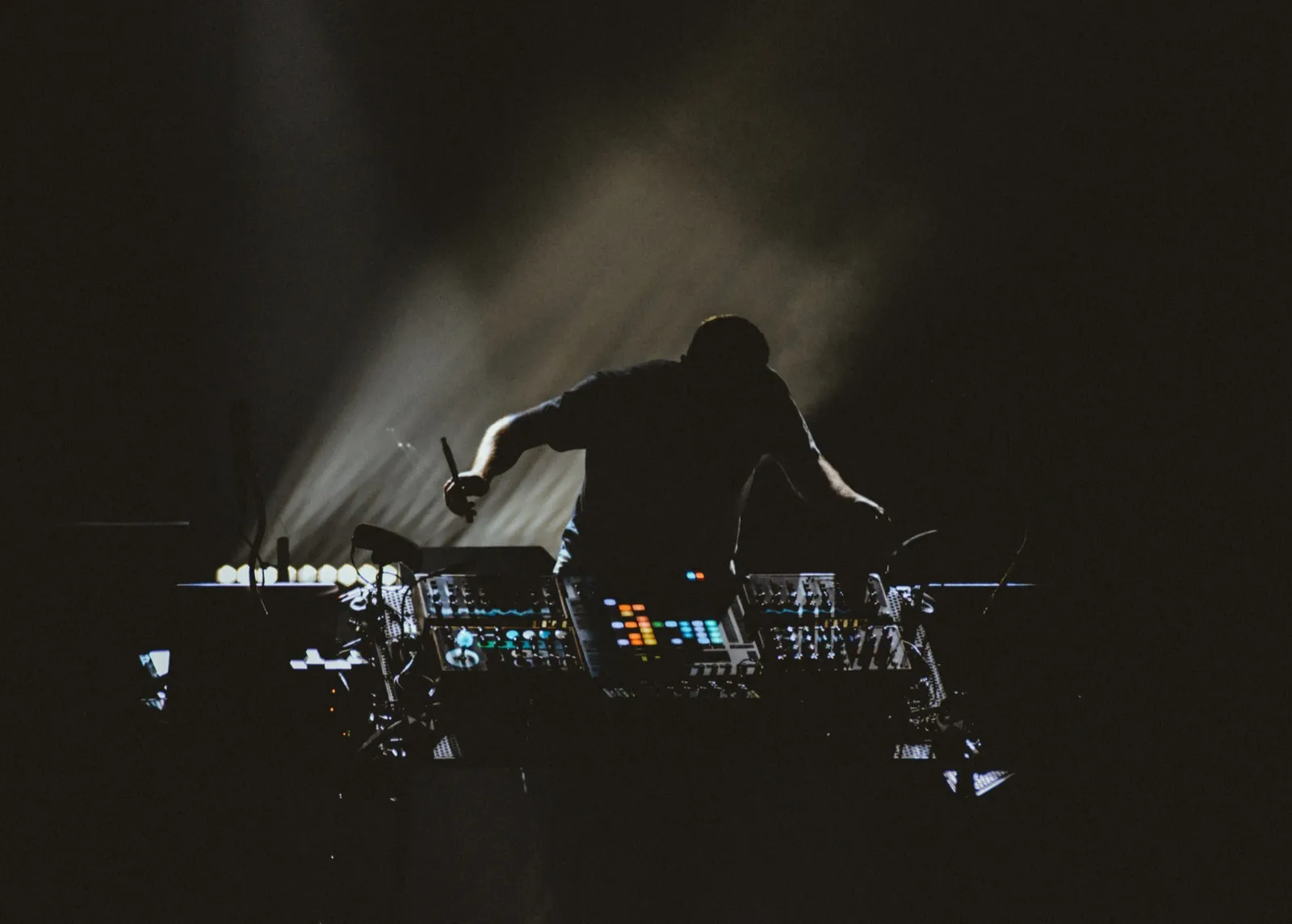 Un DJ en silhouette manipule ses platines, entouré d’un éclairage discret qui accentue l’atmosphère immersive.