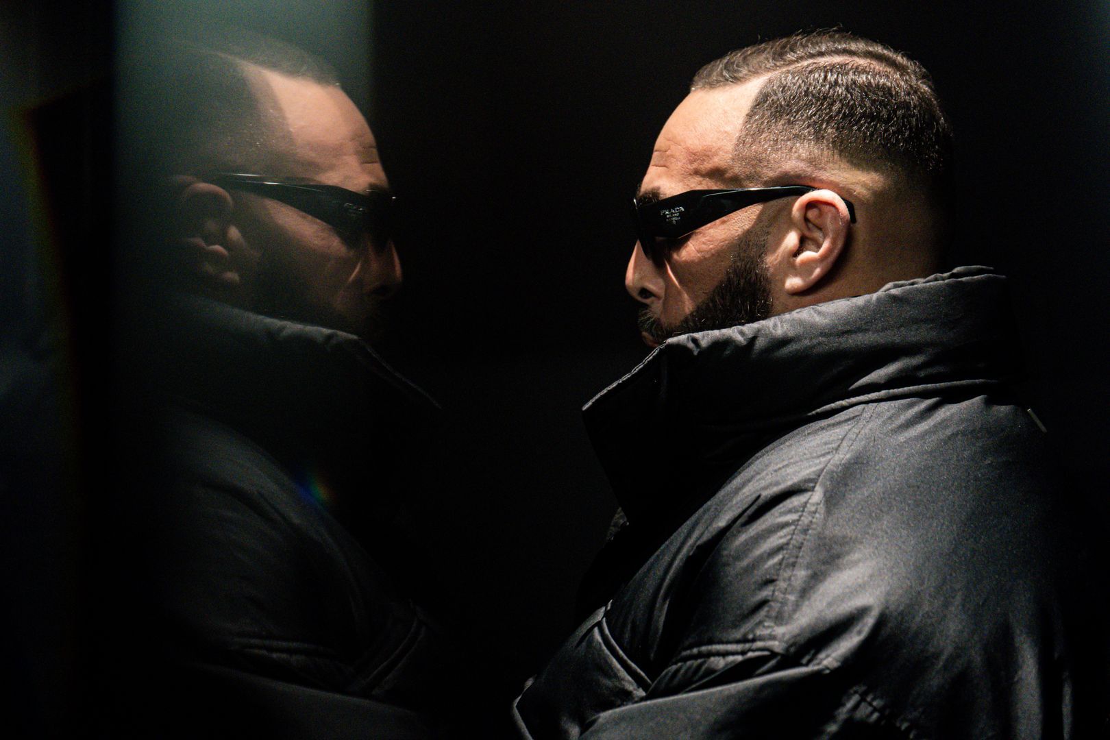 Portrait backstage d’un rappeur en blouson de cuir, reflet dans un miroir, ambiance intimiste