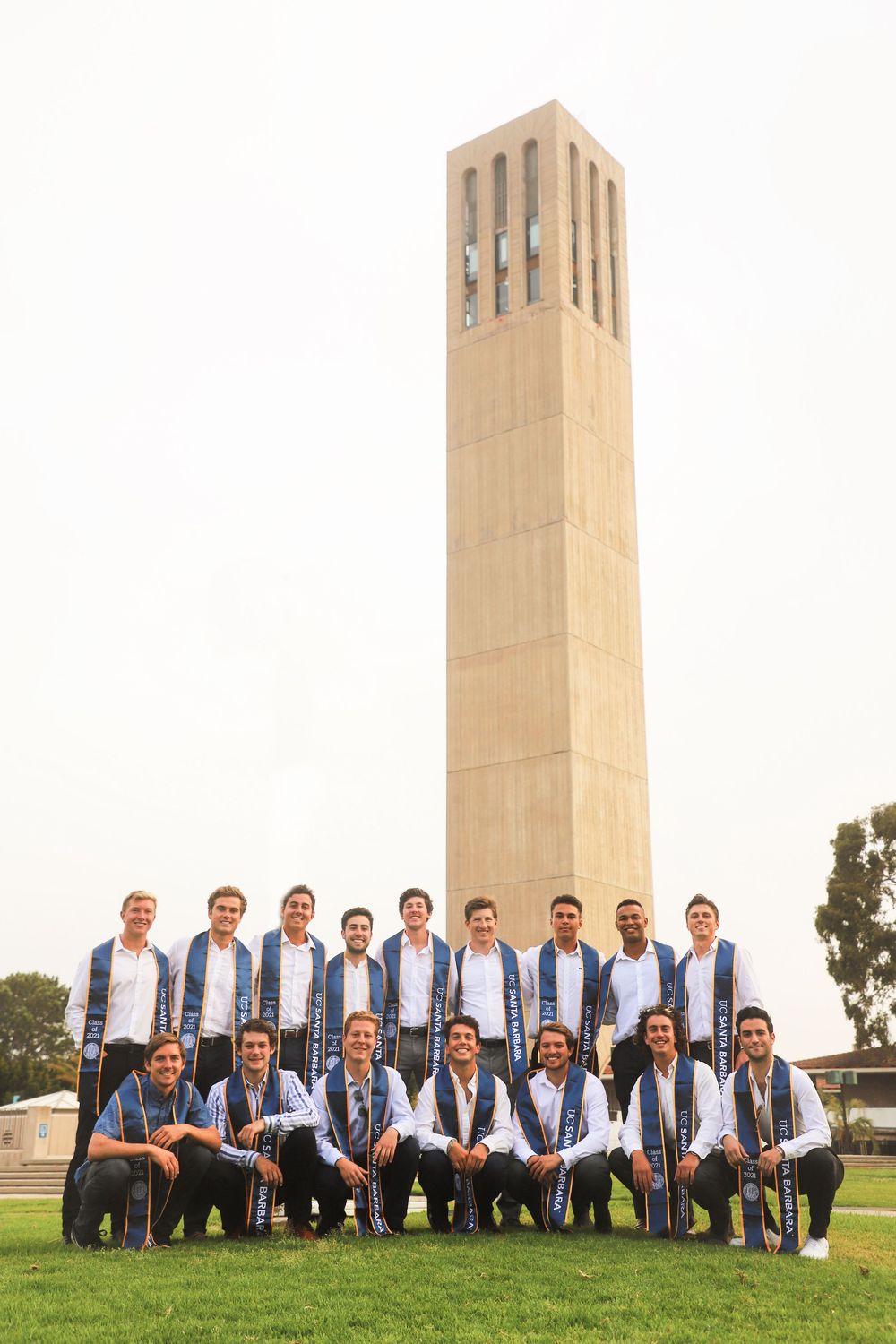 Group photo of students in matching blue and white outfits posing in front of Storke Tower at UC Santa Barbara campus.