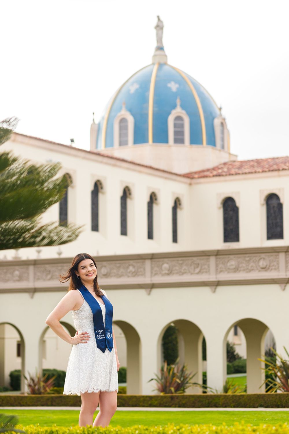 Historic Spanish-style building with blue domed roof and arched colonnade on grassy lawn at Immaculata Parish in San Diego.