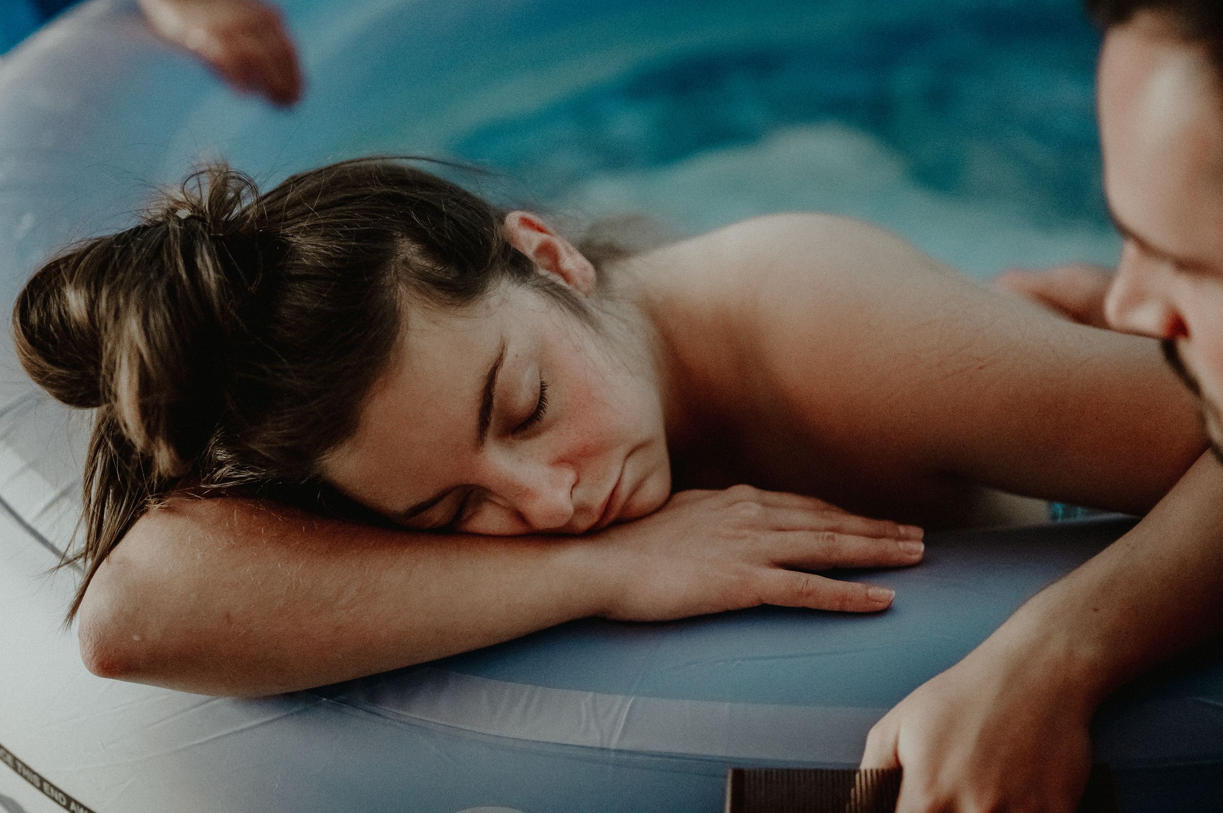A person relaxes peacefully on a massage table in a serene spa setting with soft teal lighting.