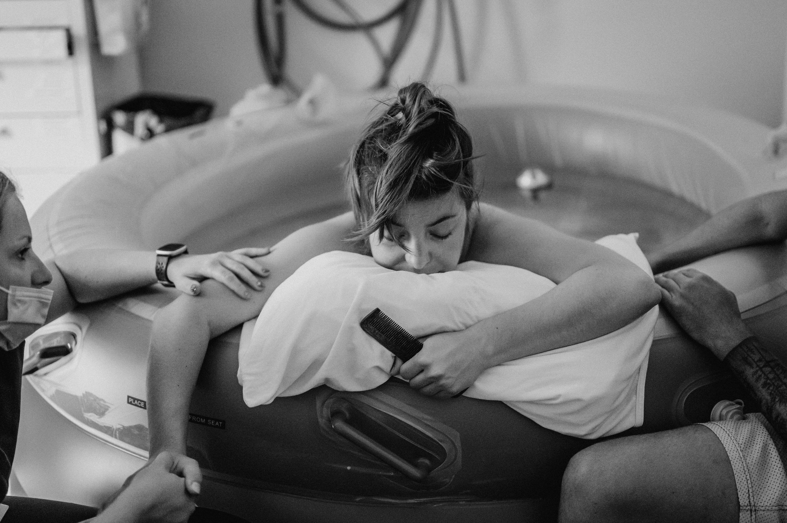Black and white image of someone resting on a dark cushion with a mobile device.