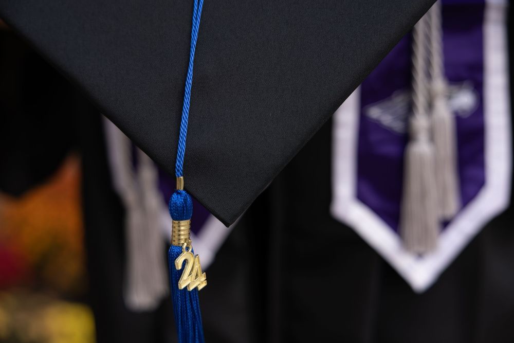 Close-up of a blue and gold graduation tassel against a dark background.