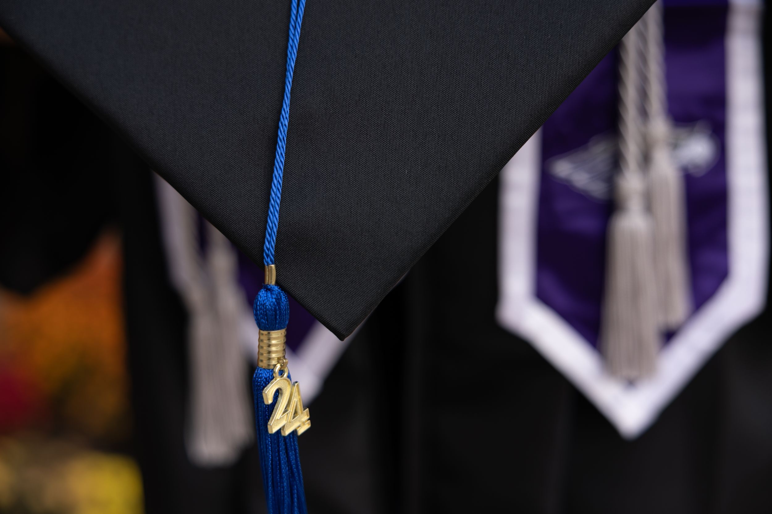 Close-up of a blue and gold graduation tassel against a dark background.